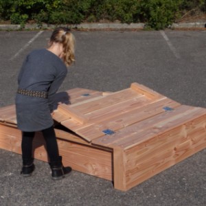 The lid of the sandbox extends slightly over the edge, minimizing the risk of finger pinching.