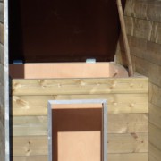 The insulated dog house is provided with a hinged roof