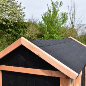 The roof of the dog kennel is provided with black roof shingles