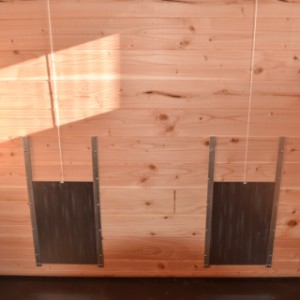On the side of the coop there are 2 pop hatches that can be easily opened and closed with a rope.